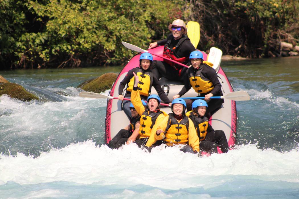 A raft crew cheering with paddles up after a rapid