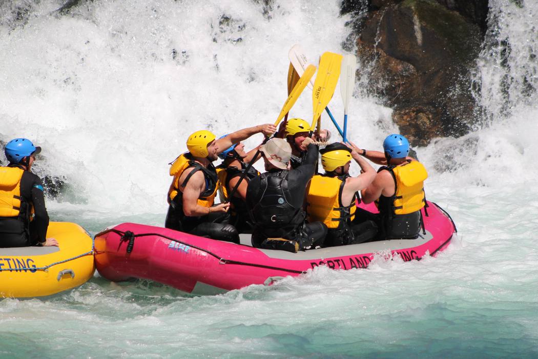 Two raft crews meeting for a paddle high-five below the falls